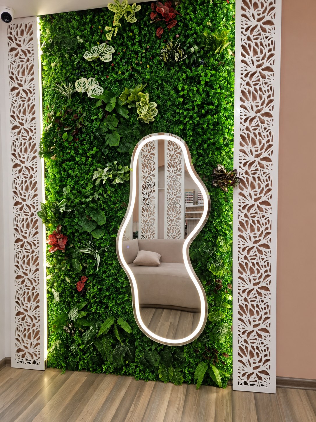 Sculptural LED mirror displayed on a green feature wall
